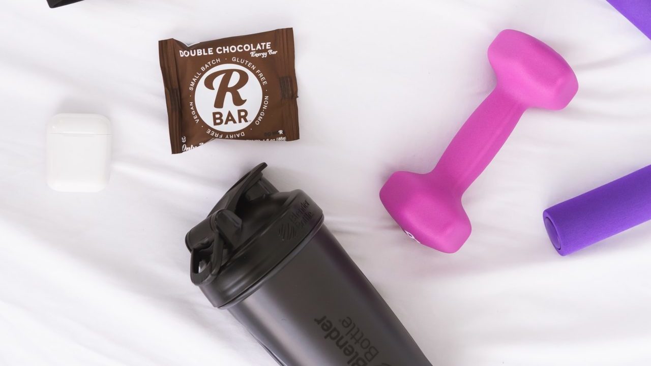 protein bar with grey protein shaker and pink dumbell