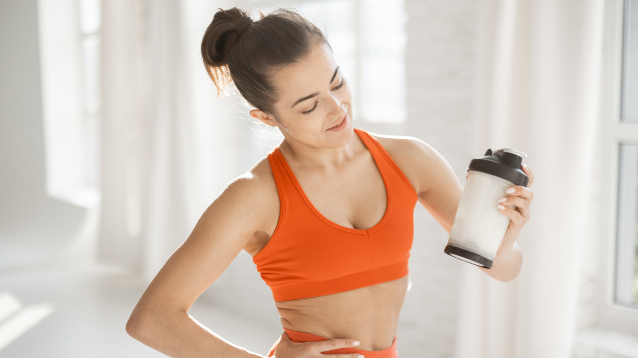 Sports woman with protein shaker at gym