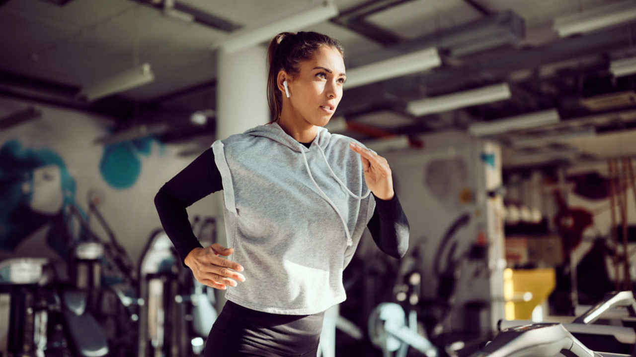 Determined athletic woman running on treadmill while practicing in a gym